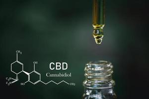 cbd kemisk formel, liten droppe dosering en biologisk och ekologisk hampa växt ört- farmaceutisk cbd olja från en burk på en grön marijuana blad bakgrund. medicinsk cannabis begrepp. foto