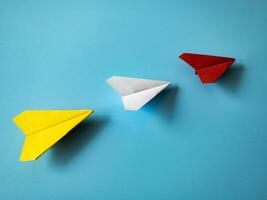 röd papper flygplan origami ledande vit och gul flygplan på blå bakgrund med anpassningsbar Plats för text. ledarskap Kompetens begrepp. foto