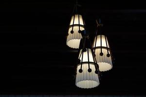 3 vit hängsmycke lampor på en svart bakgrund till stå ut och de skönhet av de ljus. mjuk och selektiv fokus. foto