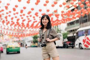 ung asiatisk kvinna ryggsäck resande njuter Kina stad gata mat marknadsföra i Bangkok, thailand. resande kontroll ut sida gator. foto