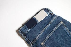 denim byxor med ett tömma läder märka på en blå bakgrund. klassisk tillbaka se av jeans från ovan med en märka layout . foto