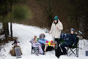 ung kvinna med barn i vinter- skog på en picknick. mor och tre ungar. foto
