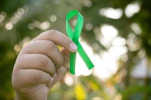 hand innehav en grön band. cancer behandling begrepp. foto