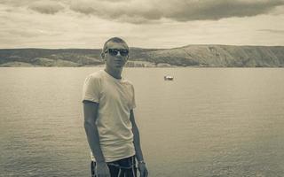 ung manlig modell med solglasögon på novi vinodolski kroatien landskap. foto