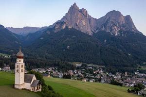 st. valentin kastelruth by kyrka i de sommar i de dolomit alperna. Fantastisk landskap med små kapell på solig äng och petz topp på kastelruth kommun. dolomiterna, söder tyrolen, Italien foto