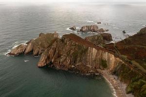 tystnad strand, silver-sandig cove stöd förbi en naturlig sten amfiteater i asturien, Spanien. foto