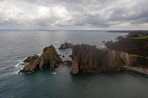 tystnad strand, silver-sandig cove stöd förbi en naturlig sten amfiteater i asturien, Spanien. foto