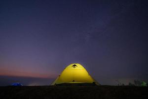 glödande gult tält och stjärnhimmel foto