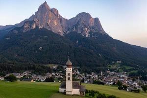 st. valentin kastelruth by kyrka i de sommar i de dolomit alperna. Fantastisk landskap med små kapell på solig äng och petz topp på kastelruth kommun. dolomiterna, söder tyrolen, Italien foto