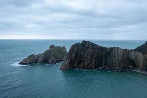 tystnad strand, silver-sandig cove stöd förbi en naturlig sten amfiteater i asturien, Spanien. foto