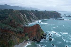 tystnad strand, silver-sandig cove stöd förbi en naturlig sten amfiteater i asturien, Spanien. foto