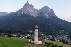 st. valentin kastelruth by kyrka i de sommar i de dolomit alperna. Fantastisk landskap med små kapell på solig äng och petz topp på kastelruth kommun. dolomiterna, söder tyrolen, Italien foto