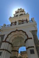 ortodox kyrka med dess mångskiktade klocka torn Fasad i emporio, santorini, grekland. foto