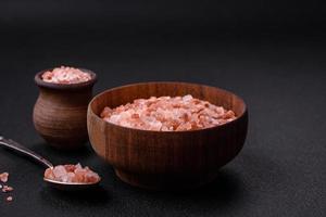 rosa himalayan salt i en trä- skål på en mörk betong bakgrund foto