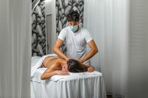 manlig massör ger en axel och tillbaka massage till lugna kvinna i spa Centrum foto