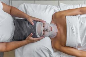kosmetolog applicering en handduk på huvud av en kvinna vem är täckt henne ansikte med flor för hud behandling foto