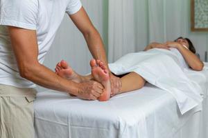 kvinna tar emot en fot zonterapi massage på spa foto