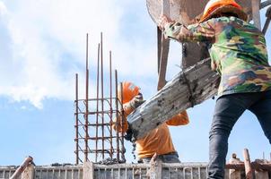 konstruktion byggnad arbetare på konstruktion webbplats häller betong i form, man arbetssätt på höjd med blå himmel på konstruktion webbplats foto