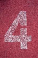 siffra fyra på löpning Spår. vit Spår siffra på röd sudd racerbana, textur av löpning kapplöpningsbanor i stadion foto