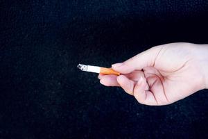 hand är innehav en cigarett på svart bakgrund, nej rökning. Avslutning från missbruk begrepp. foto