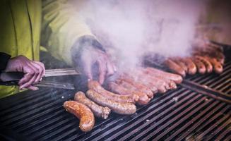 en närbild se av händer av en man grillning hemlagad korvar foto