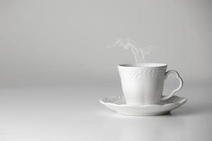 vit kopp och fat av te eller kaffe med ånga på vit bakgrund. keramisk kopp eller råna med varm dryck. mock-up klassisk porslin redskap. kopia Plats foto