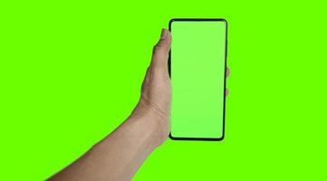 hand innehav en grön smartphone på en grön bakgrund foto