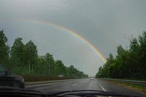 se av de väg från de bil fönster, där är en regnbåge i de himmel foto