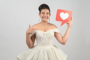 asiatisk skön brud leende och Framställ med hjärta tecken på vit bakgrund foto
