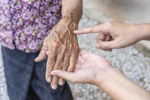 dotters fingrar poäng till rynkig hand. åldring bearbeta - mycket gammal senior kvinnas händer rynkig hud, effekt av ålder på de hud, gammal ålder. rynkig hud och framträdande ådror. äldre kvinnas händer foto