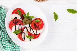 traditionell italiensk caprese sallad med mozzarella, tomat, basilika och balsamisk vinäger. topp se, över huvudet foto