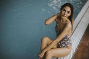 vacker ung kvinna sitter vid poolen foto