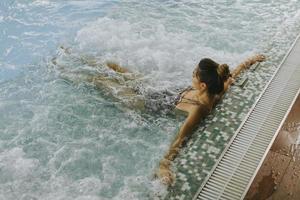 ung kvinna som kopplar av i bubbelpoolen vid poolen foto