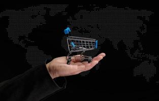 mannens hand innehar en miniatyr- handla vagn på en mörk bakgrund, begrepp av de Start av värld försäljning foto