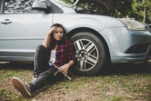 ung hipsterkvinna med ett litet däck på sin bil foto