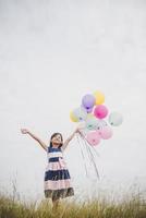 liten flicka som leker med ballonger på ängfältet foto