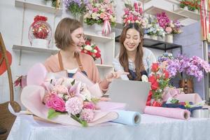 två ung skön kvinna blomsterhandlare partners diskutera flora knippa dekoration, uppkopplad inköp order och hemsida arrangemang för företag, Lycklig arbete i färgrik blomma affär Lagra, och e-handel sme. foto