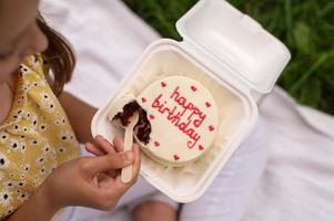 söt bebis bryter en choklad födelsedag bento kaka med en trä- sked foto