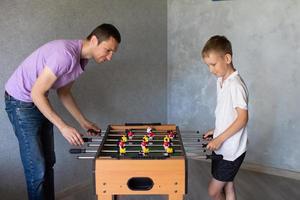 söt pojke spelar tabell fotboll med hans emotionell pappa i de rum foto