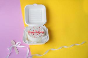 en små bento födelsedag kaka i en låda. trä- båt med vit band foto