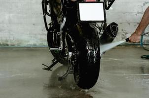 högtrycksvattenpistol som tvättar en motorcykel i biltvättbutiken foto