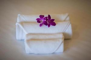 vita handdukar på sängen med lila blommor