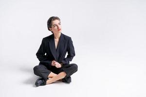 skön ung affärskvinna i trendig svart kostym Framställ Sammanträde på golv foto