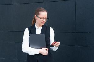 caucasian företag lady i kostym innehav bärbar dator och talande på telefon, Framställ foto