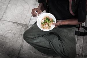 fattig man hemlös med smutsig händer äter äter mat på gata väg golv i de stad modern kapitalism samhälle foto