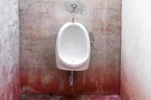urinoar på gammal betong röd vägg, skrämmande toalett foto