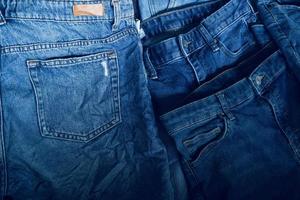 tyg textur, stänga upp av blå denim jean textur med tillbaka ficka detalj..förstörd trasig klassisk denim blå jeans plåster, baner mode bakgrund foto