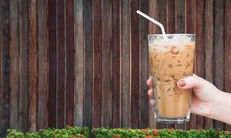 kvinna hand innehav de glas iced kaffe på trä- bakgrund, iskall latte kaffe foto