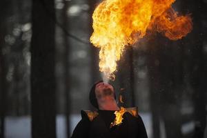 de man har brand och rök kommande ut av hans mun. fireshow.young man blåser brand från hans mun foto