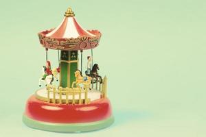 årgång leksak karusell på ett smaragd- bakgrund. röd klockspel med karusell, retro karusell foto